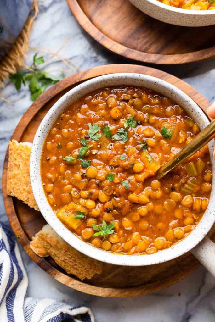 Curried Tomato Lentil Soup on a wooden plate with a side of bread