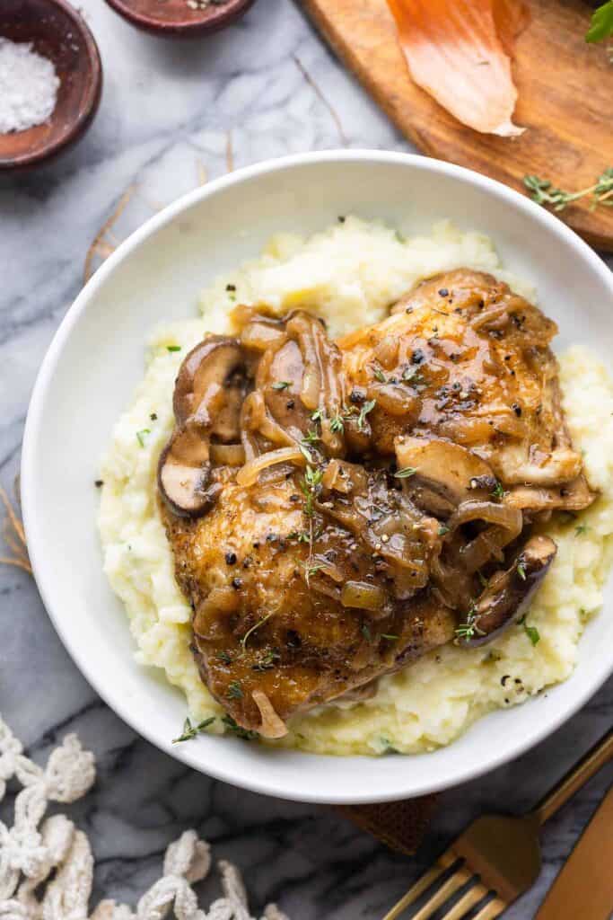 Apple Cider Braised Chicken Thighs in a bowl over mashed potatoes