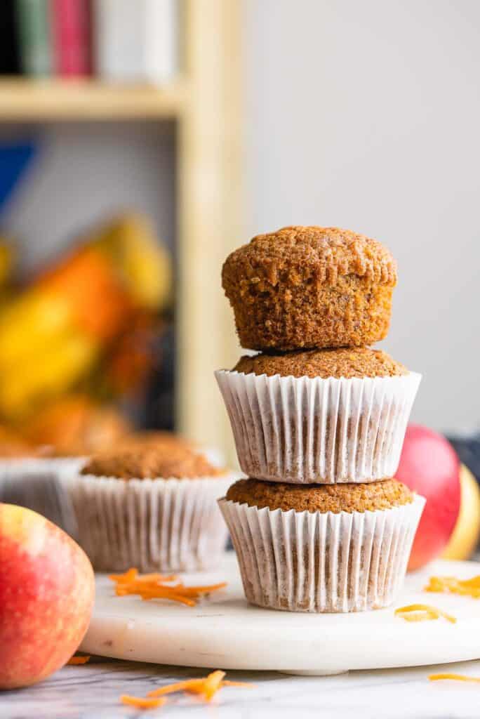 a stack of 3 Carrot & Apple Flaxseed Muffins - the top muffin without a paper liner