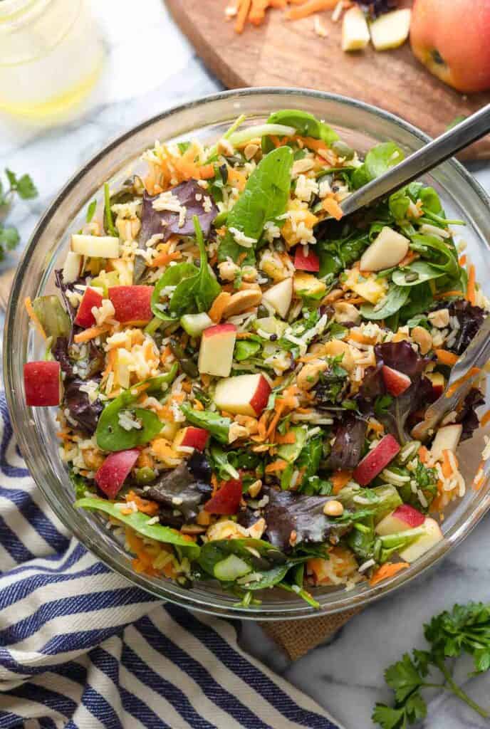 fall rice salad in a mixing bowl surrounded by fresh parsley