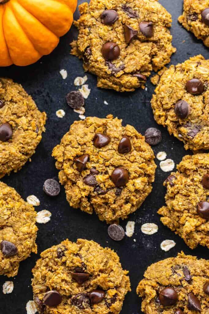 healthy oatmeal pumpkin cookies with chocolate chips on a baking sheet sprinkled with oats