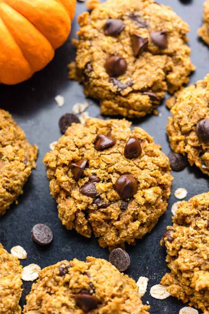 an up close picture of an oatmeal pumpkin cookies with chocolate chips on a baking sheet sprinkled with oats