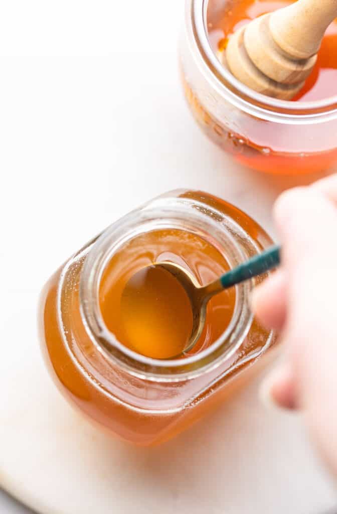 honey simple syrup in a jar with a spoon mixing it
