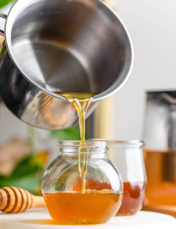 a milk pot pouring a honey simple syrup into a small jar