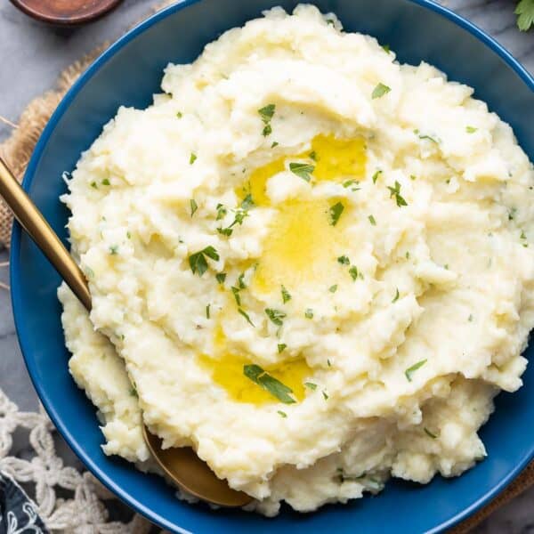 mashed cauliflower and potatoes in a serving bowl with melted butter on top