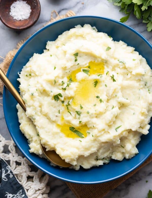 mashed cauliflower and potatoes in a serving bowl with melted butter on top