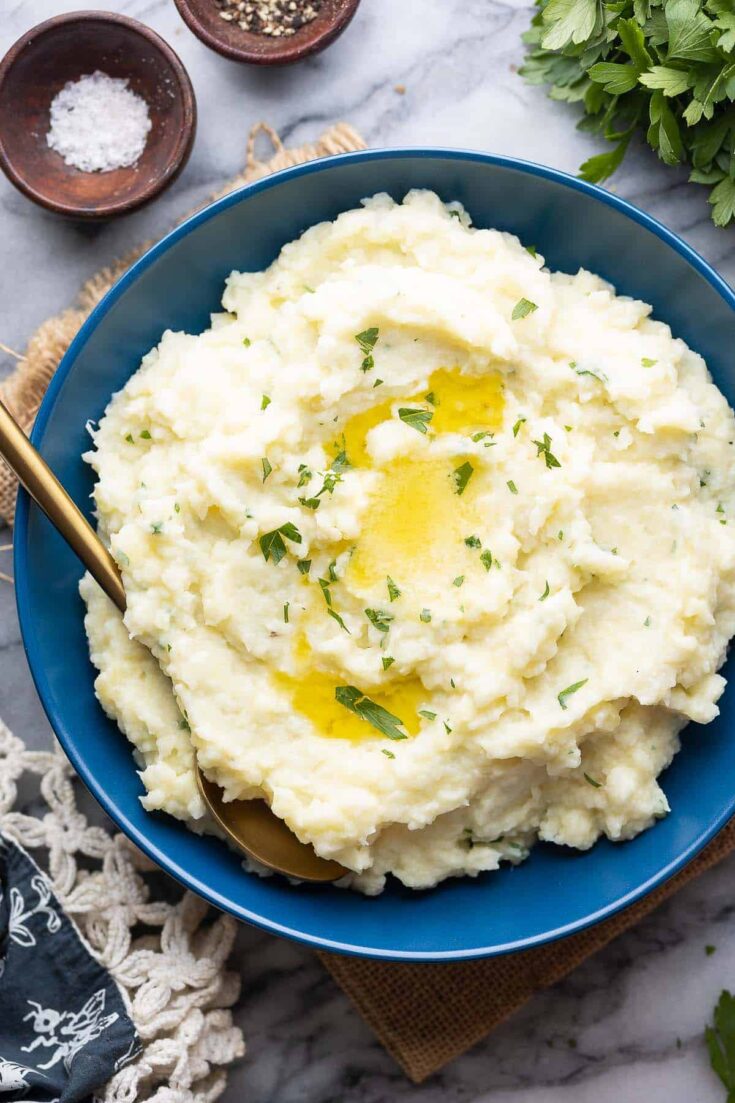 mashed cauliflower and potatoes in a serving bowl with melted butter on top