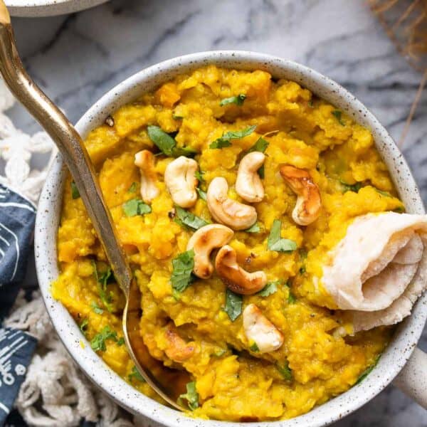 red lentil dahl in a bowl topped with toasted cashews