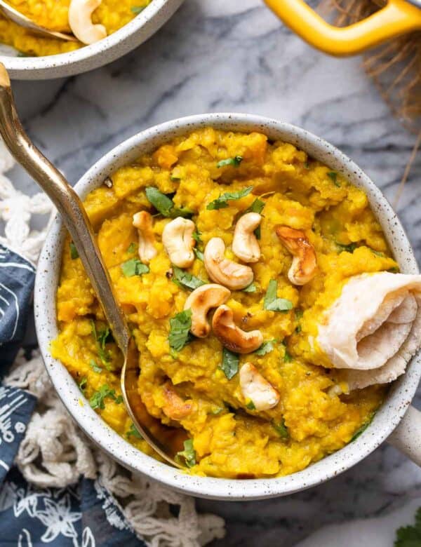 red lentil dahl in a bowl topped with toasted cashews