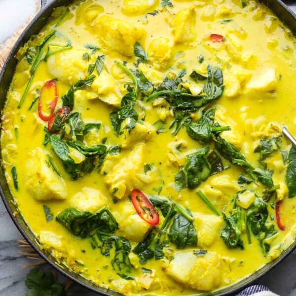 spinach turmeric fish curry in a cast iron pan
