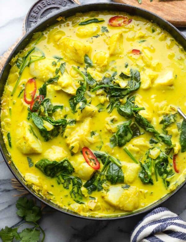 spinach turmeric fish curry in a cast iron pan