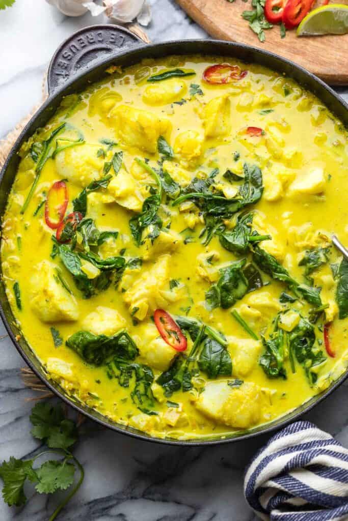 spinach turmeric fish curry  in a cast iron pan