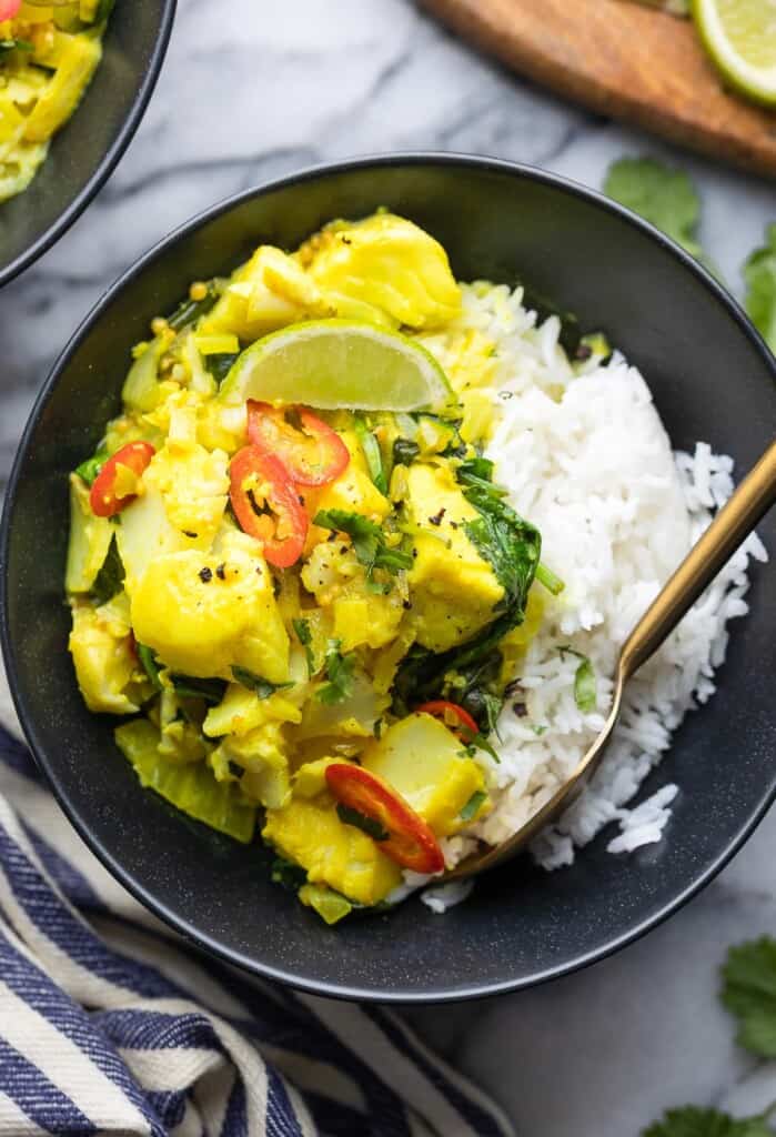 spinach turmeric fish curry in a serving bowl over a bed of rice