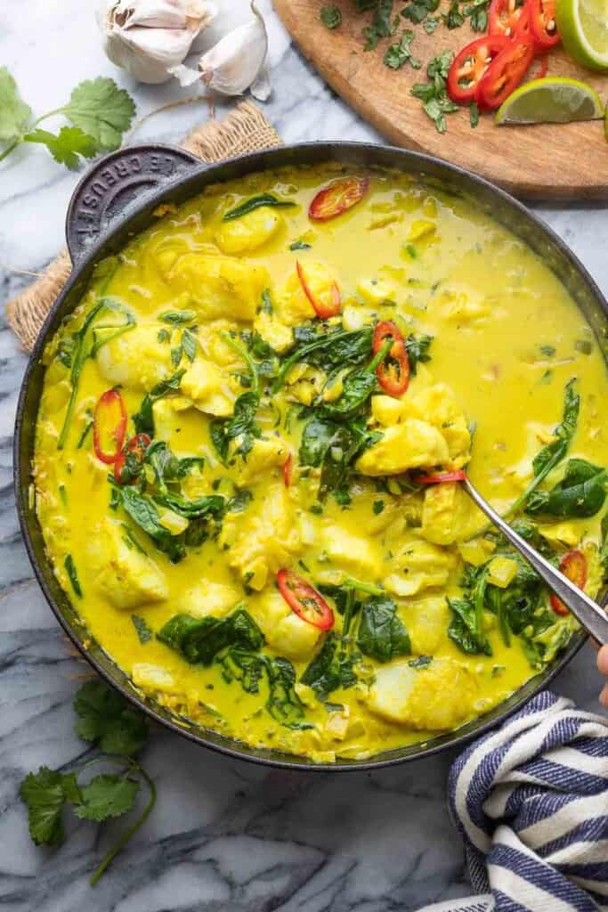 a serving spoon scooping up some spinach turmeric fish curry 