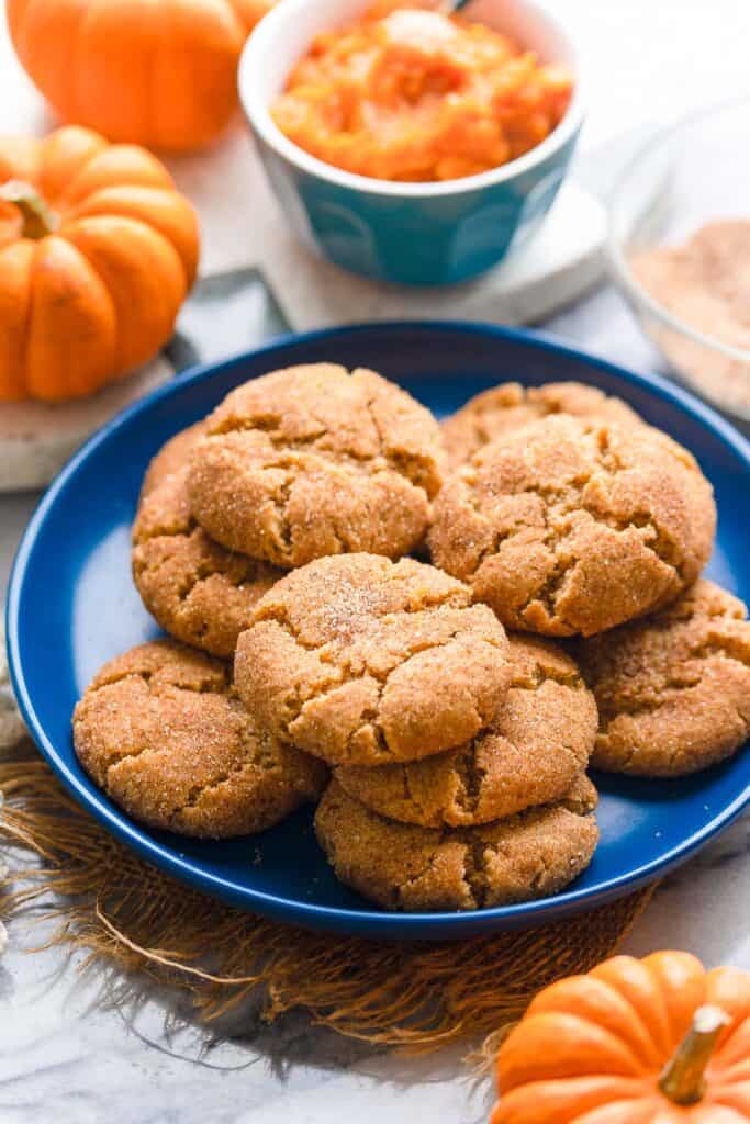 a plate of pumpkin snickerdoodles with a bowl of pumpkin puree in the back