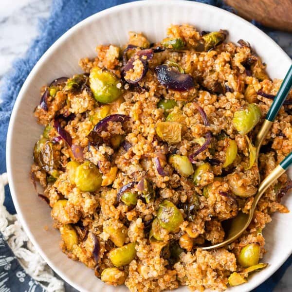 Roasted Brussels Sprouts Quinoa Salad mixed into a red pesto vinaigrette in a salad bowl