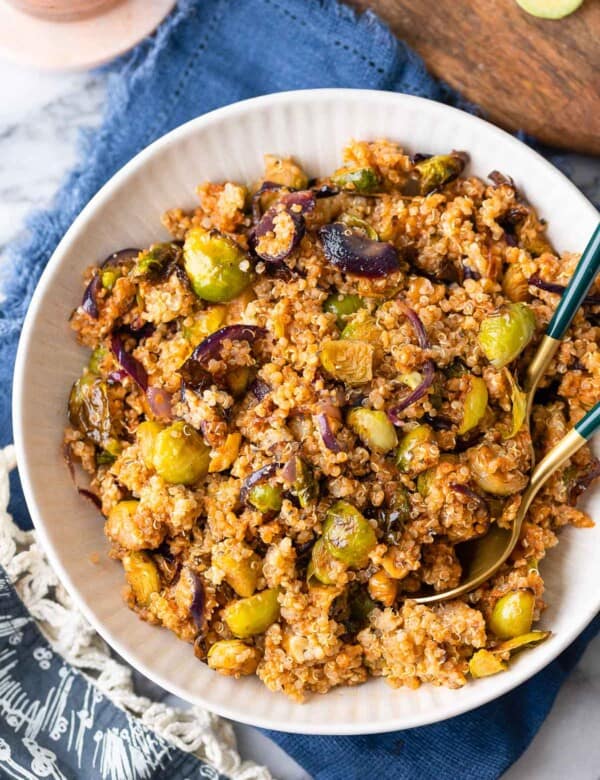 Roasted Brussels Sprouts Quinoa Salad mixed into a red pesto vinaigrette in a salad bowl