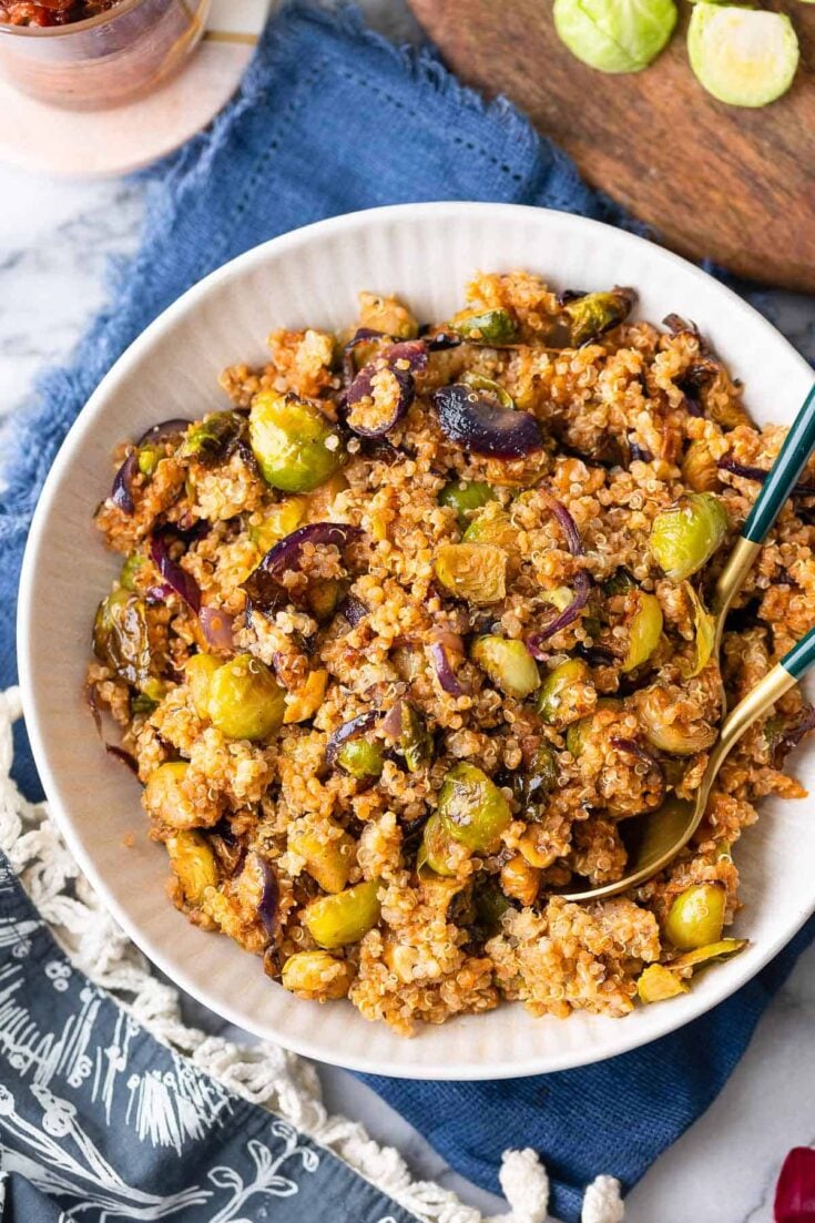 Roasted Brussels Sprouts Quinoa Salad mixed into a red pesto vinaigrette in a salad bowl