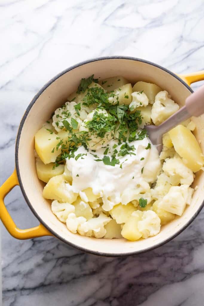boiled mashed potatoes with cauliflower in pot with herbs and yogurt