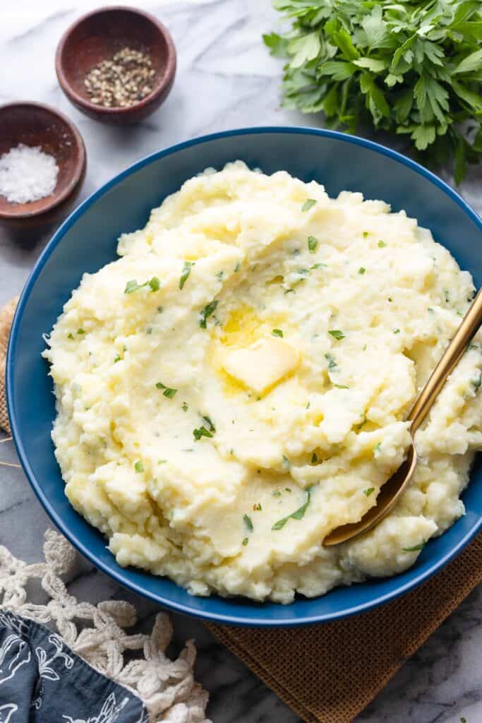 Mashed Potatoes with Cauliflower in a serving bowl with melted butter on top