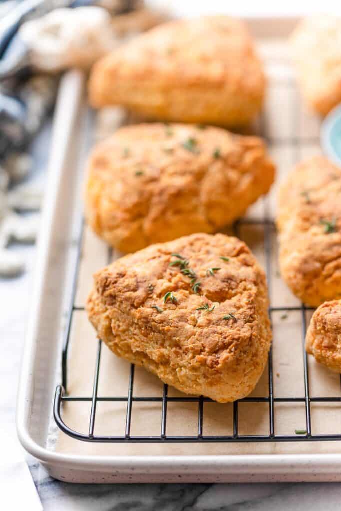 gluten free cheese scones cooling on a wire rack with fresh thyme leaves on top