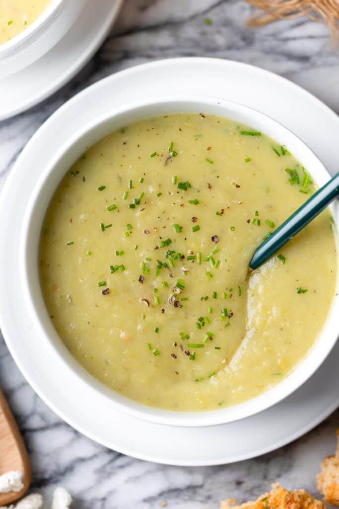 a bowl full of potato leek soup with fresh chives on top