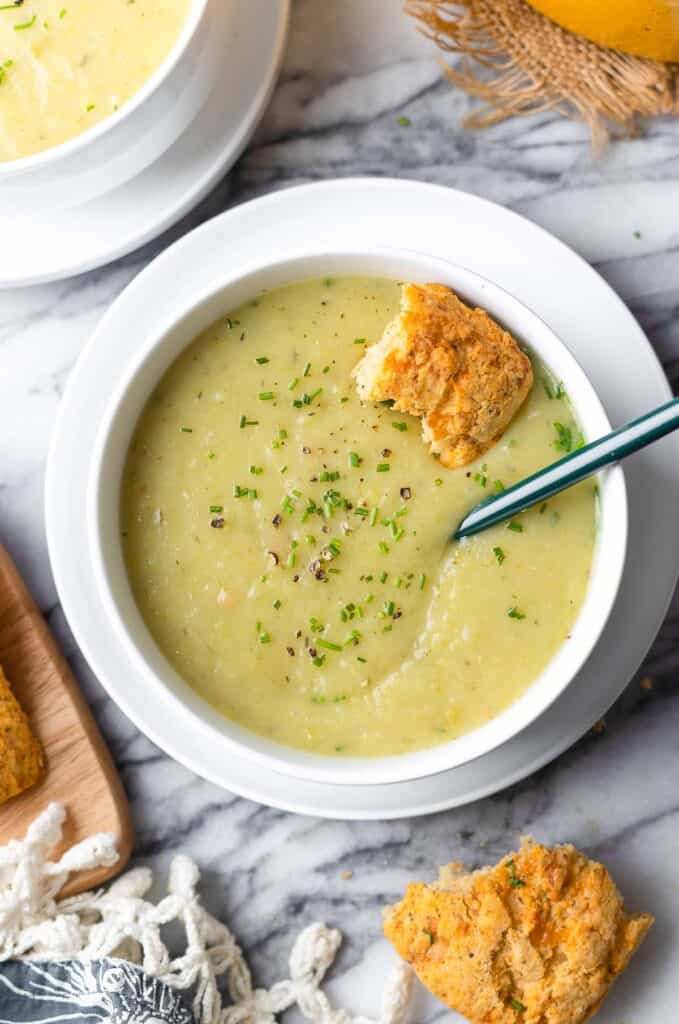 Leek and Potato Soup in a bowl with fresh chives and a cheesy biscuit inside