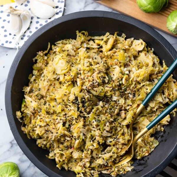 Spiced Garlic Sautéd Brussels Sprouts in a salad bowl with serving spoons