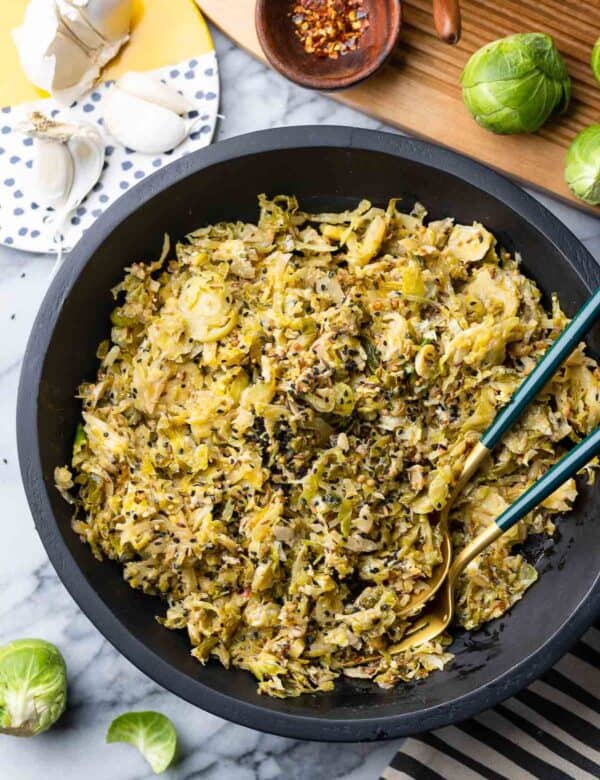 Spiced Garlic Sautéd Brussels Sprouts in a salad bowl with serving spoons