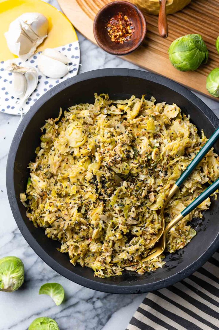 Spiced Garlic Sautéd Brussels Sprouts in a salad bowl with serving spoons