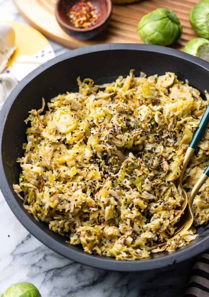 Sautéed Brussels Sprouts topped with whole mustard, nigella and cumin seeds in a salad bowl 