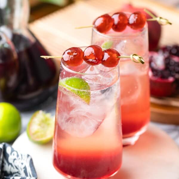 two shirley temple mocktails in high ball glasses with cherries on toothpicks to garnish