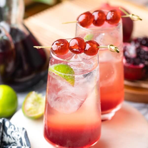 two shirley temple mocktails in high ball glasses with cherries on toothpicks to garnish