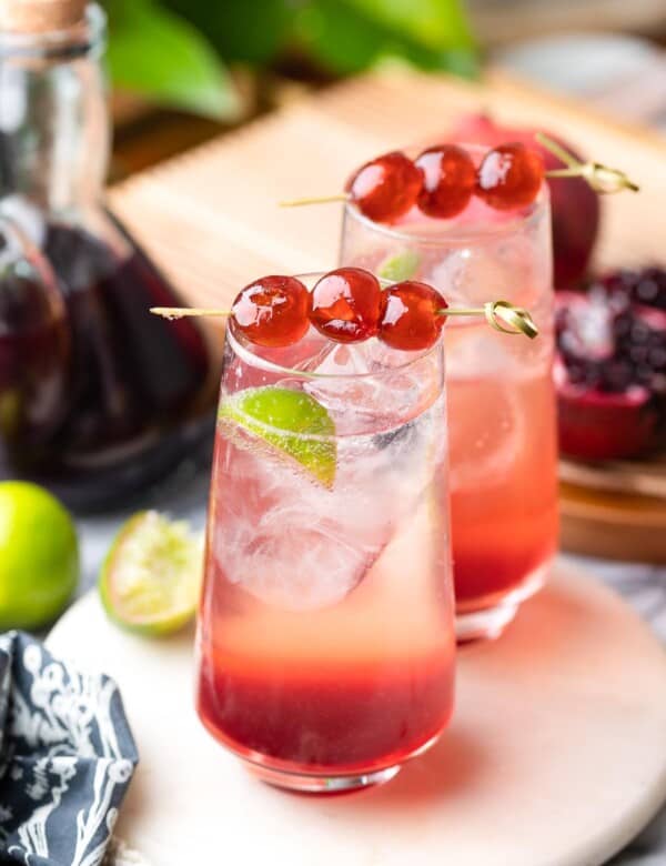 two shirley temple mocktails in high ball glasses with cherries on toothpicks to garnish