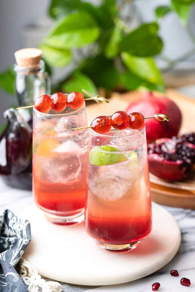 two Shirley Temple Cocktails in tall glasses with lime wedges and maraschino cherries on top