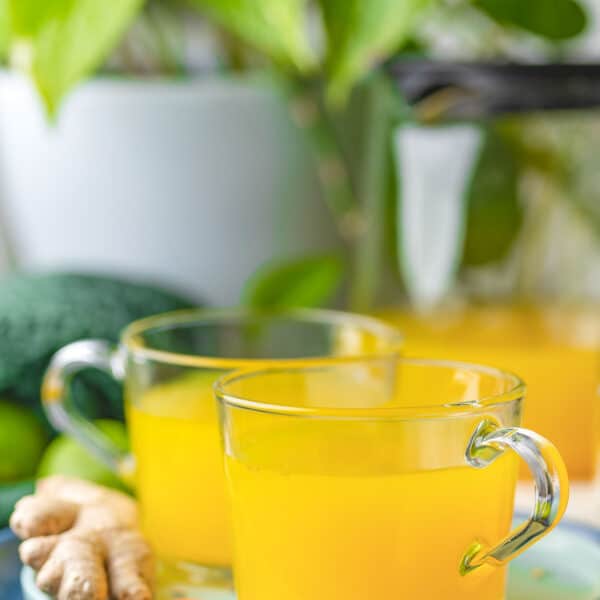 two mugs of ginger lime turmeric tea on a plate