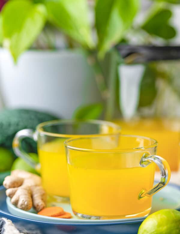 two mugs of ginger lime turmeric tea on a plate