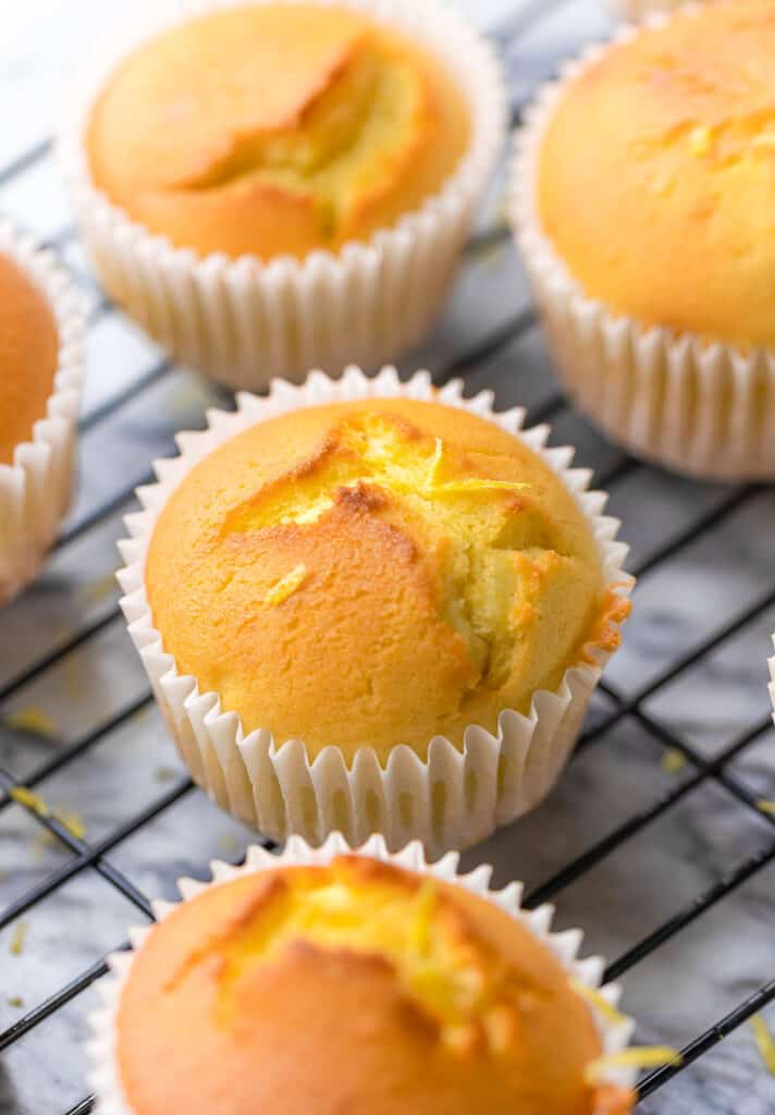 Spanish Gluten Free lemon muffins (Magdalenas) on a wire rack with lemon zest grated over the top