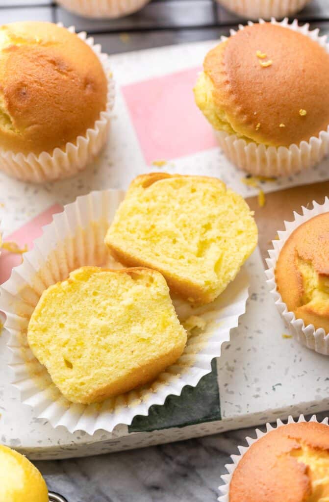 a Gluten Free lemon muffin cut in half to show the soft inside of the muffin sitting on a serving platter