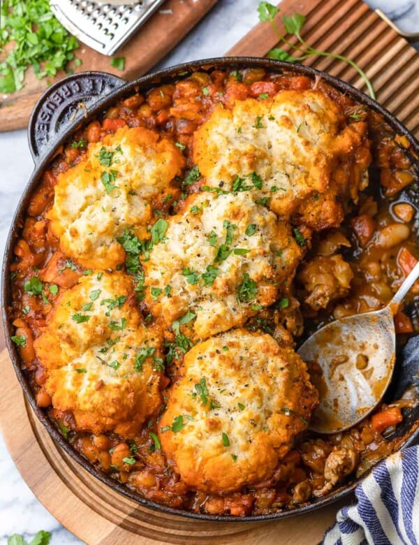 Italian Chicken & White Bean Stew with Parmesan Biscuits in a cast iron pan with a serving spoon