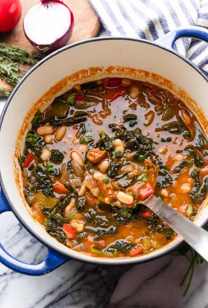 Spanish Chorizo and White Bean Soup in a large soup pot with a ladle full of soup