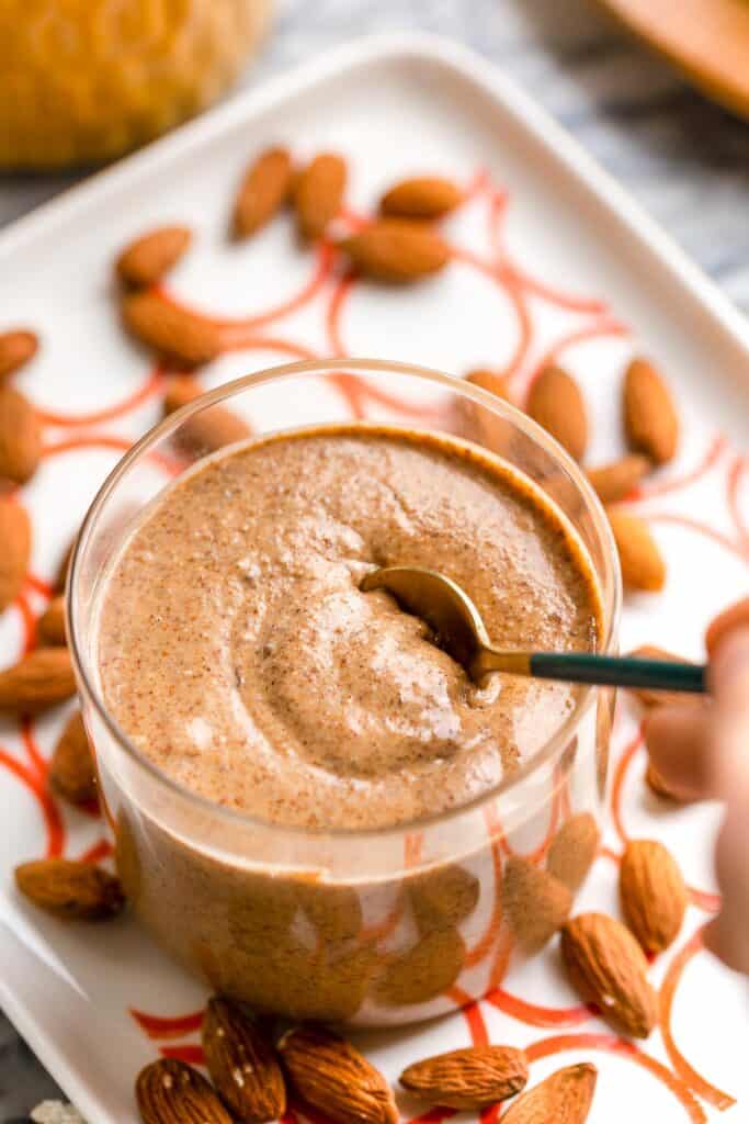 homemade almond butter in a small jar with a spoon scooping some up