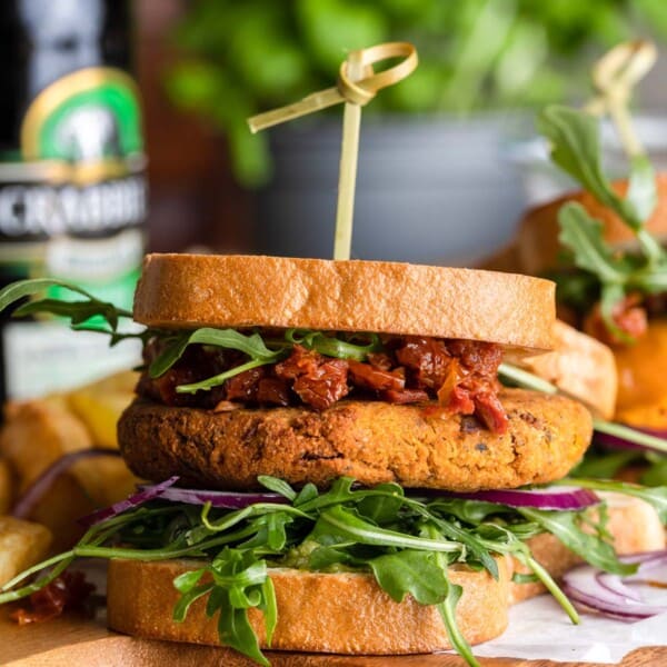 sun dried tomato chickpea burger with chopped sun dried tomatoes and arugula on a cutting board