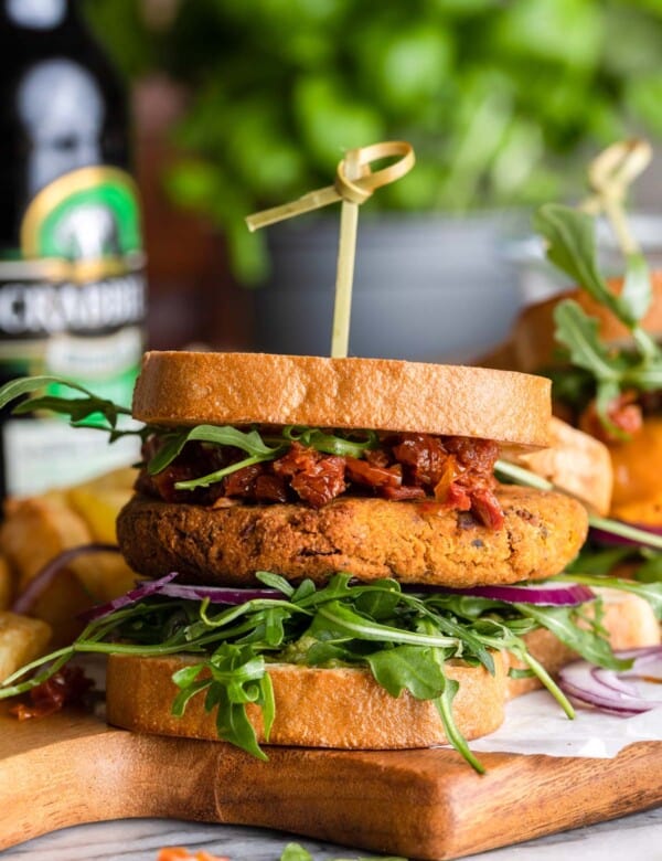 sun dried tomato chickpea burger with chopped sun dried tomatoes and arugula on a cutting board