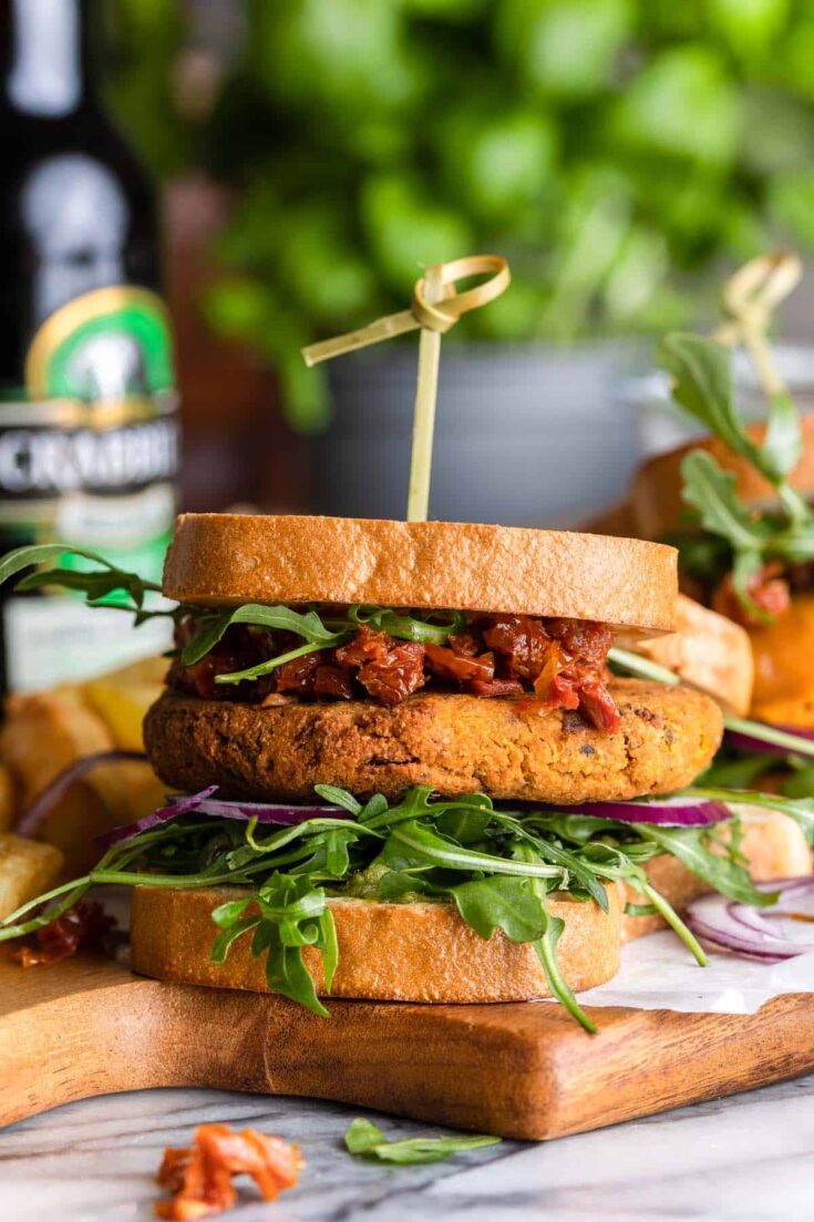 sun dried tomato chickpea burger with chopped sun dried tomatoes and arugula on a cutting board