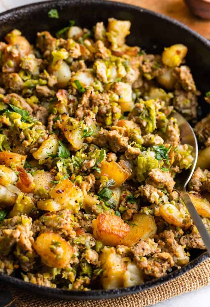 a spoon scooping up a serving of Crispy Potato & Leek Turkey Hash 