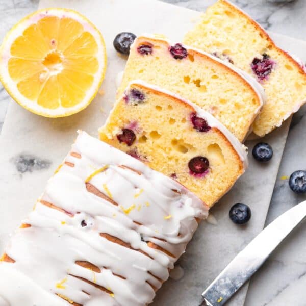 gluten free blueberry loaf cake sliced and surrounded by fresh lemons and berries