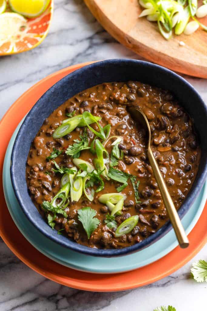 Adobo Black Beans in a serving bowl topped with sliced spring onions and fresh cilantro