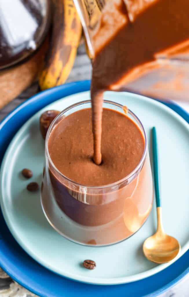 chocolate coffee smoothie pouring from a blender jug into a cup