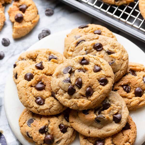 Chocolate Chip Peanut Butter Cookies made with Millet Flour on a small platter with more cooking cooling on a wire rack behind